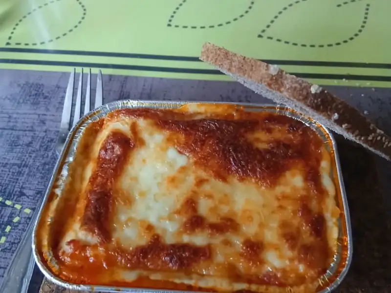 Lasagne monoporzione fatte in casa: una vaschetta di alluminio ben gratinata con una fetta di pane tostato